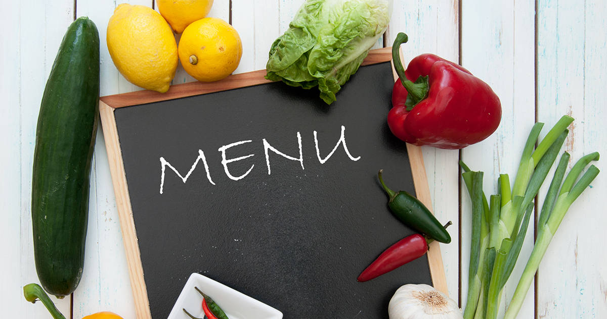 fresh vegetables surrounding a chalkboard with "menu" written on it