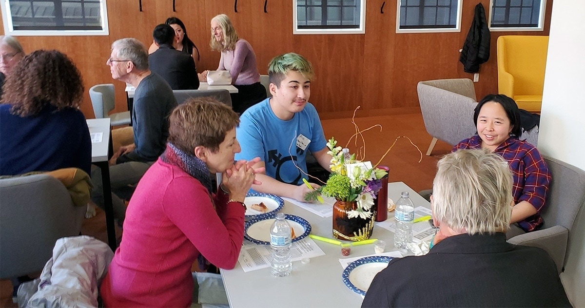 young man with green hair discusses the LGBTQ generation gap with Avenidas members at the LGBTQ Cafe