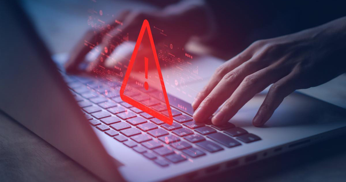 danger sign projected over hands typing on a laptop