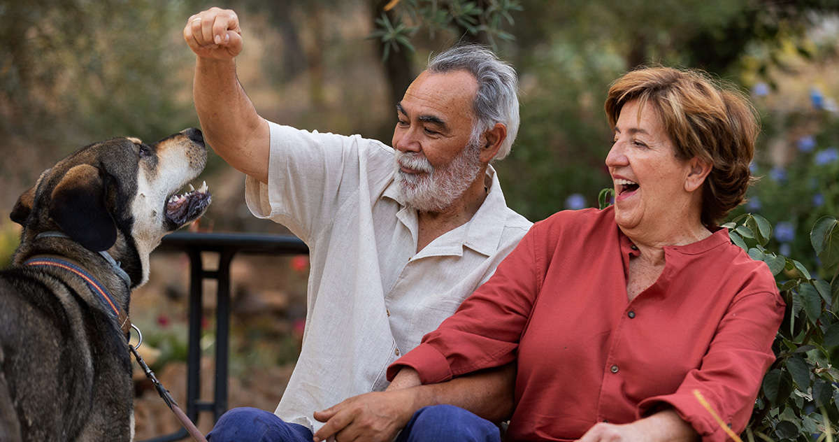 Senior couple playing with a large dog on a leash