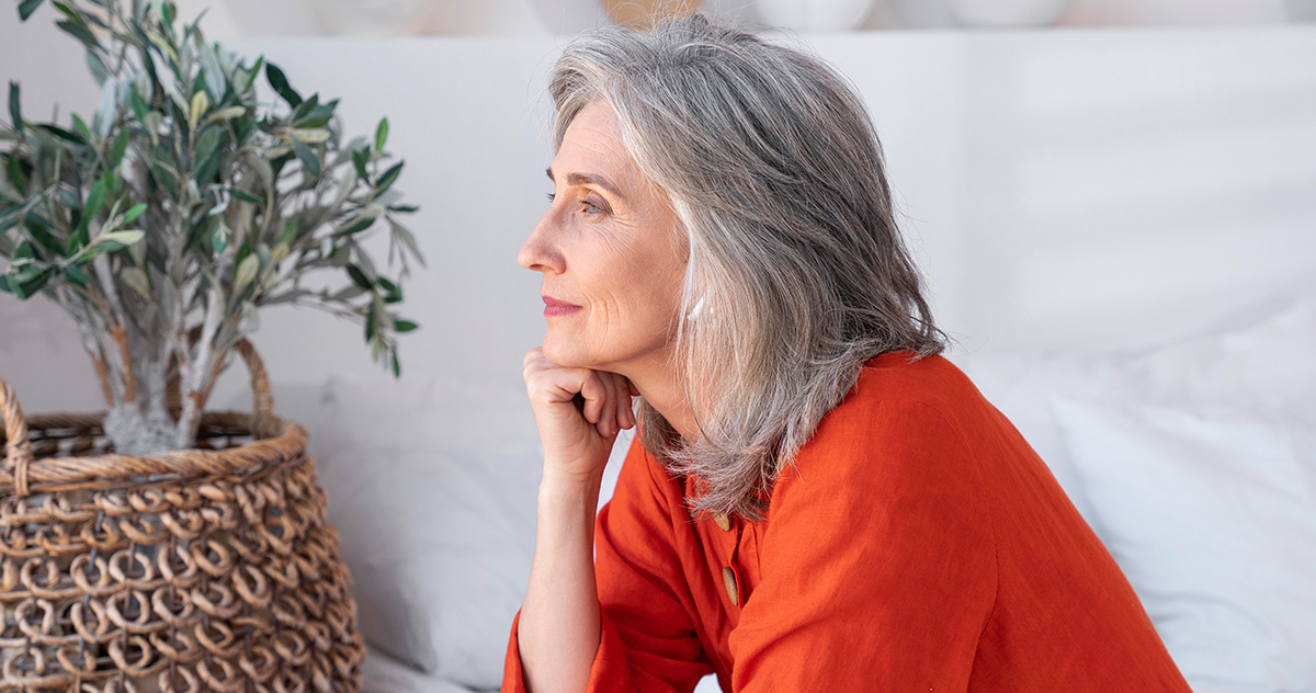 Senior woman in red shirt gazing thoughtfully into the distance